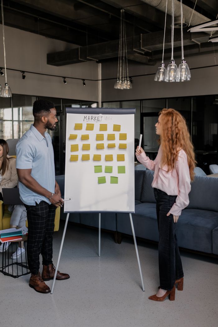 about-us Colleagues collaborating on marketing strategy with sticky notes on a whiteboard in a modern office setting.